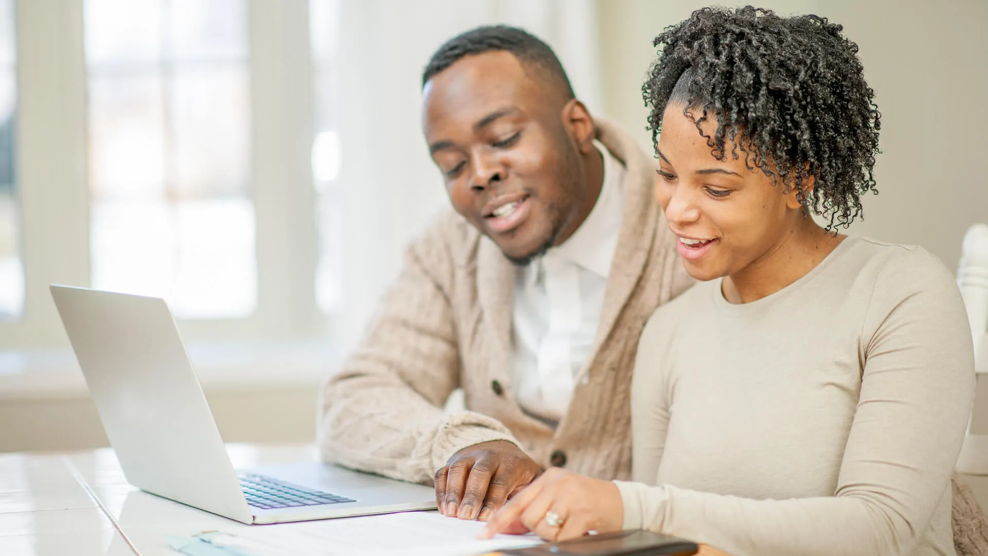 A husband and wife are sitting together at their dinner table and are balancing their budget.