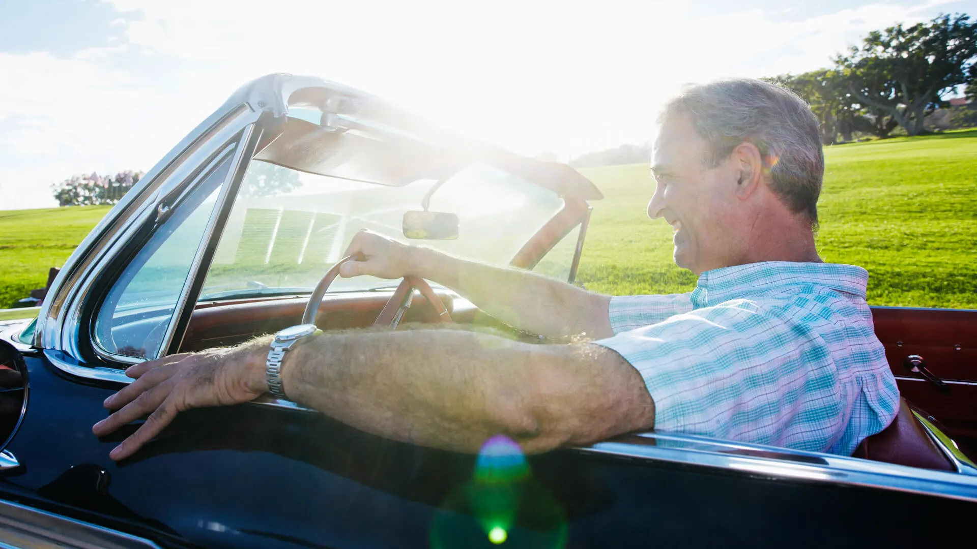 Caucasian man driving classic convertible.