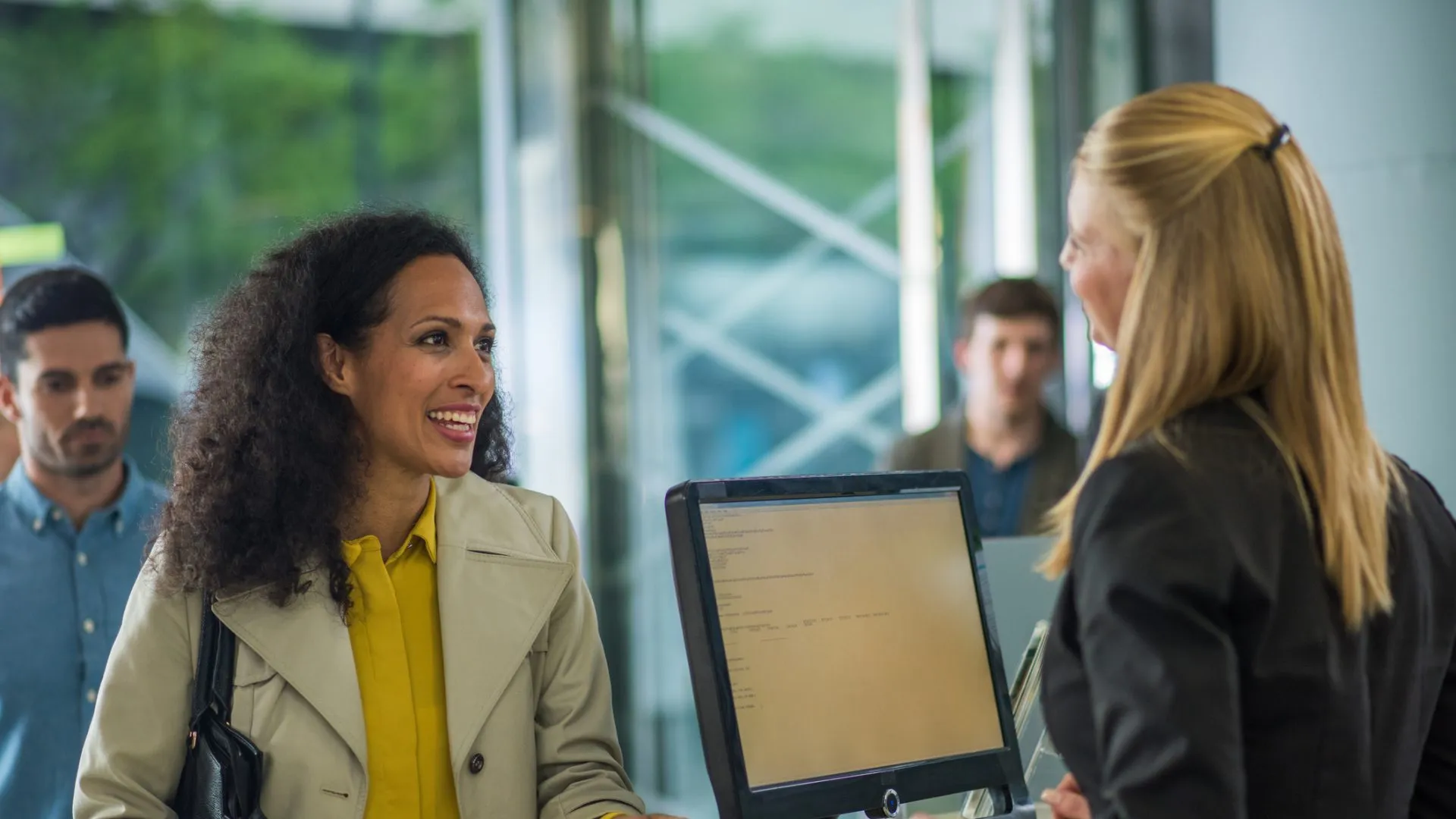 Customer holding document and smiling while bank teller serving.