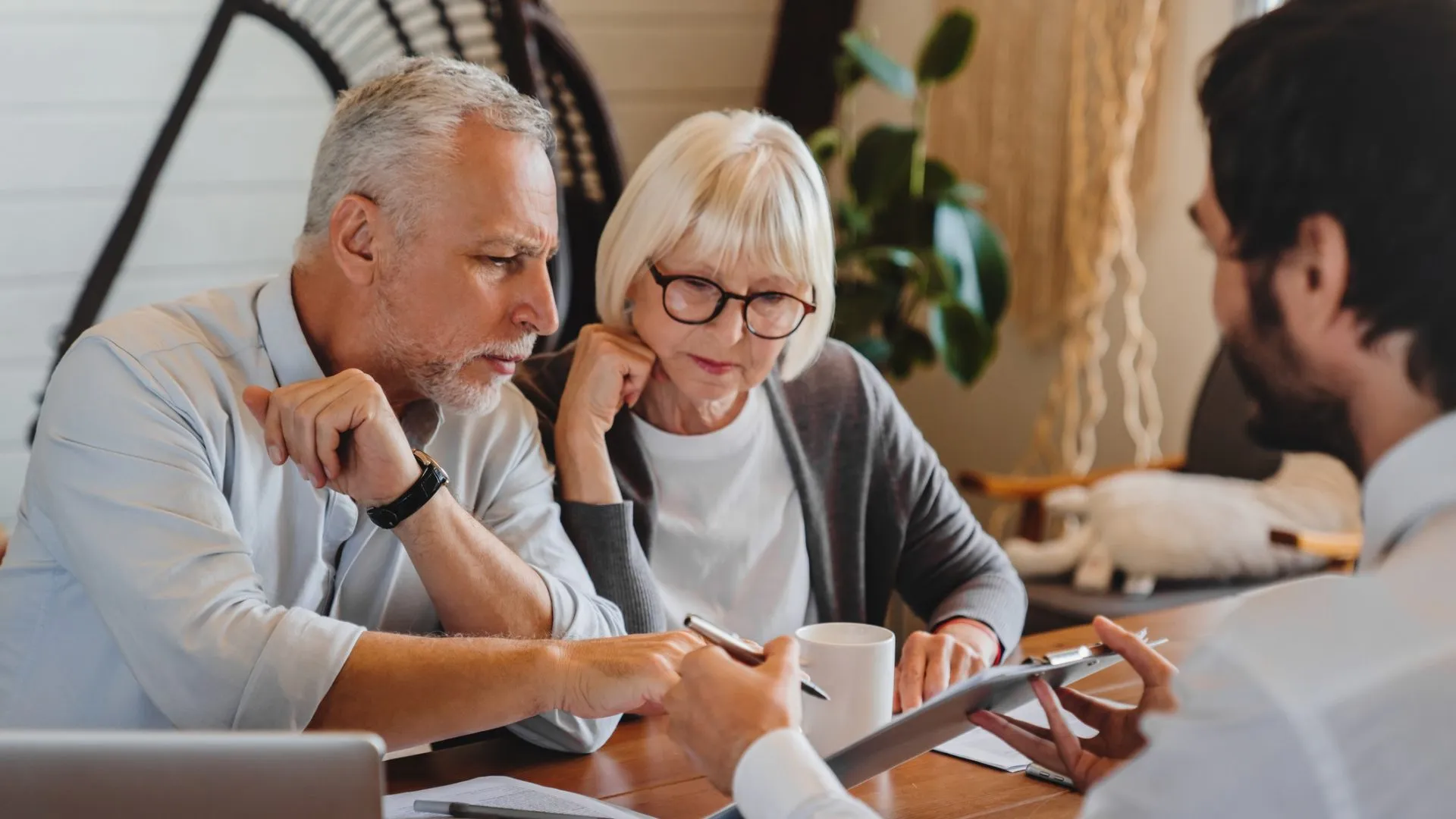 Financial advisor explaining paperwork to elderly retired couple front of desk.