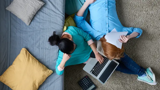 Directly above view of exhausted couple trying to cope with taxes, they doing paperwork together.