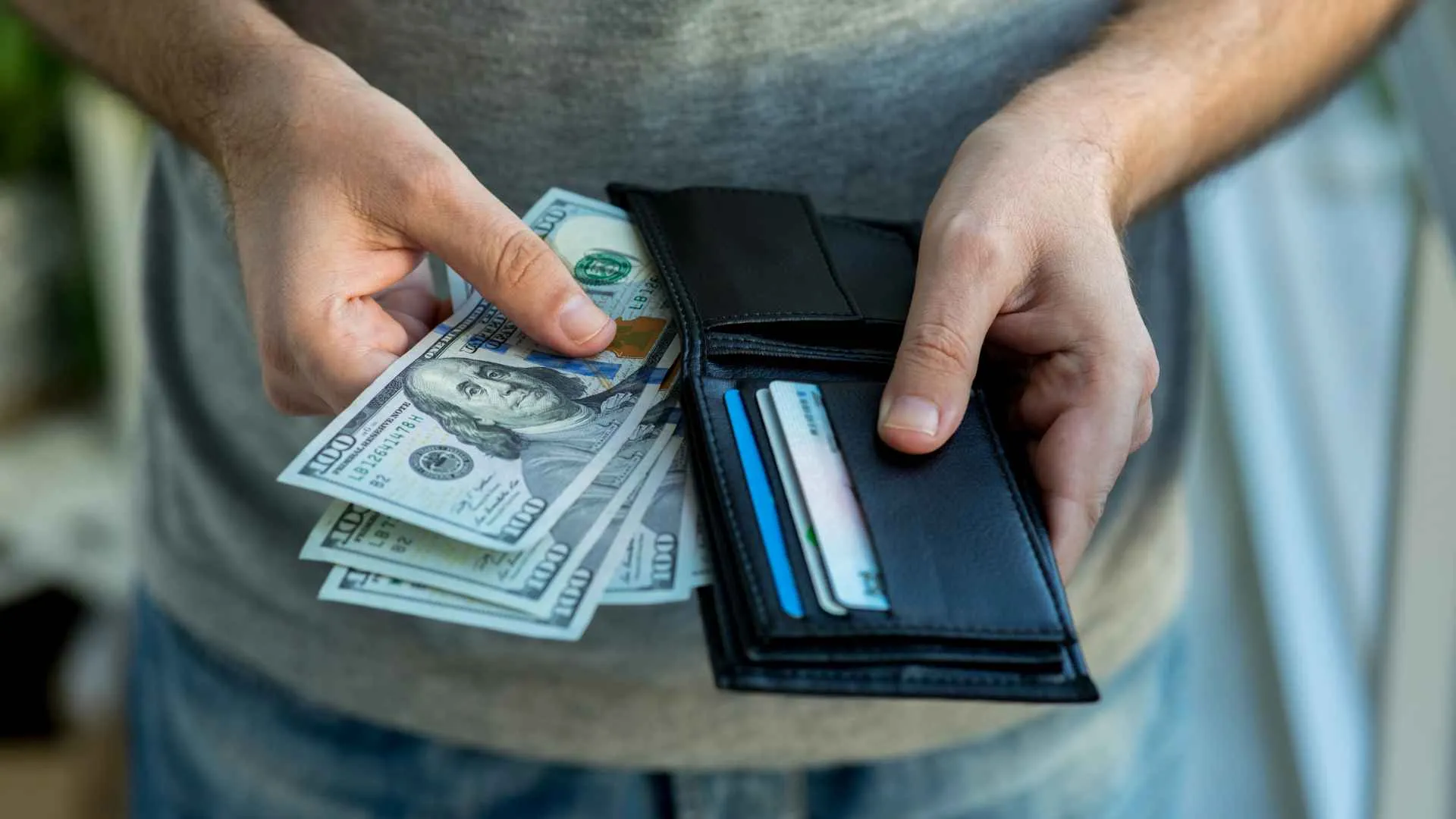 Man placing USA Dollar bills into wallet.