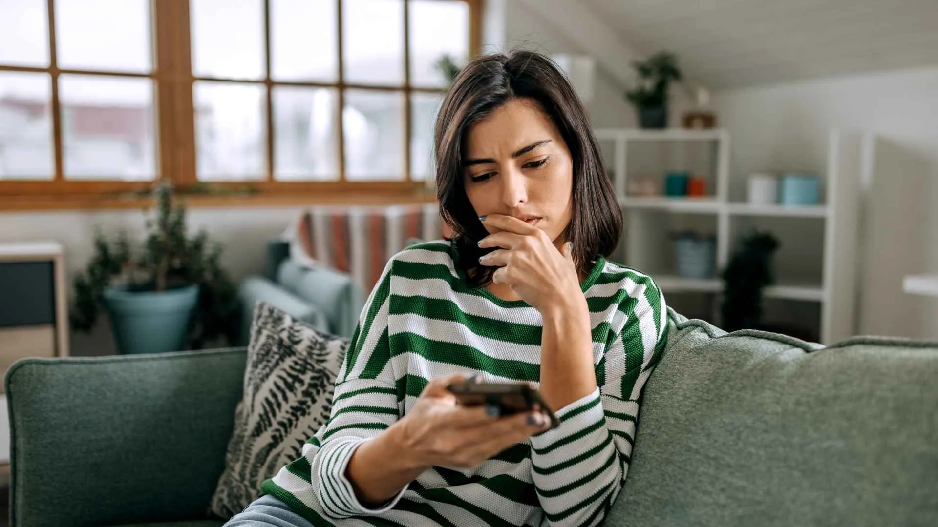 A woman seems sad and worried as she looks at her phone.