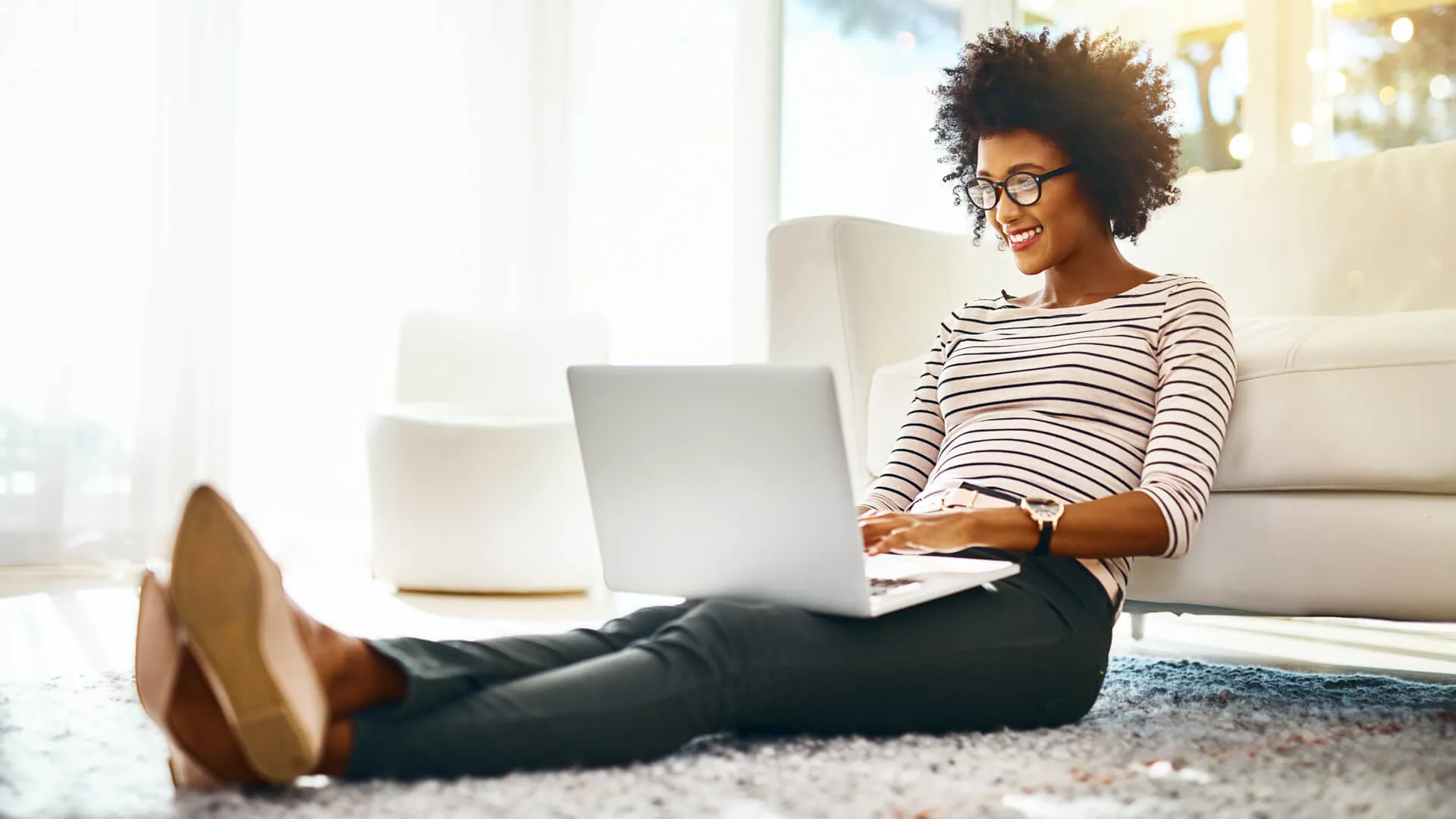 Shot of a cheerful young woman doing online shopping on her laptop while being seated on the floor at home.