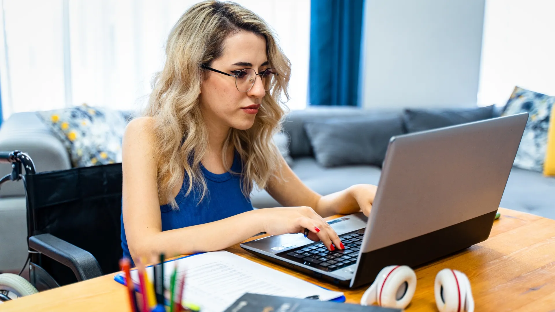 disabled woman sitting in wheelchair at the table and looking at computer monitor.